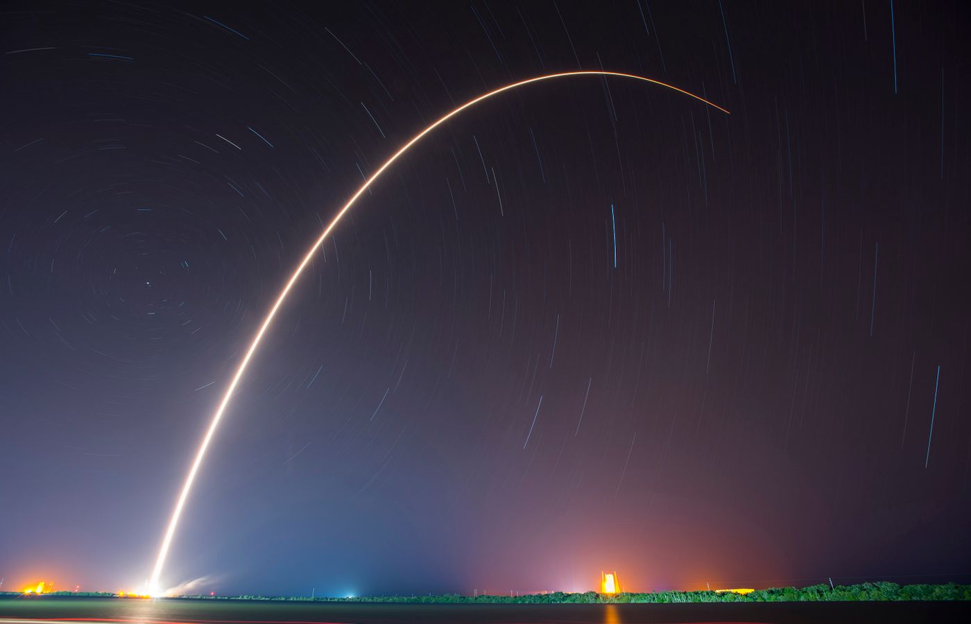 Long-exposure arc of a rocket launching at night